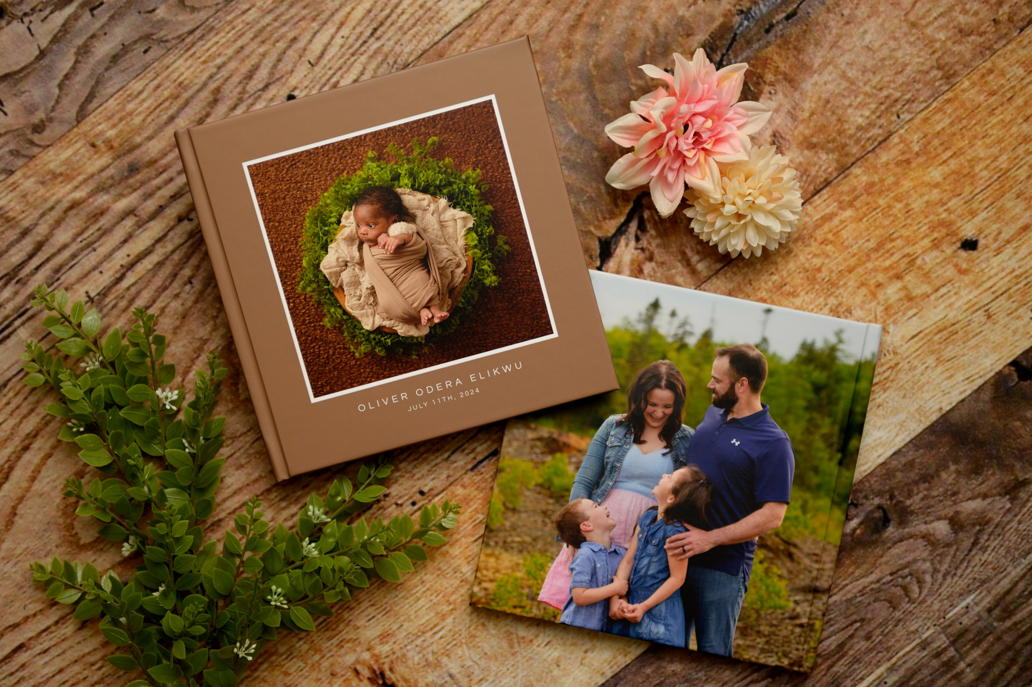 two custom photo albums lying on the floor arranged with flowers and greenery