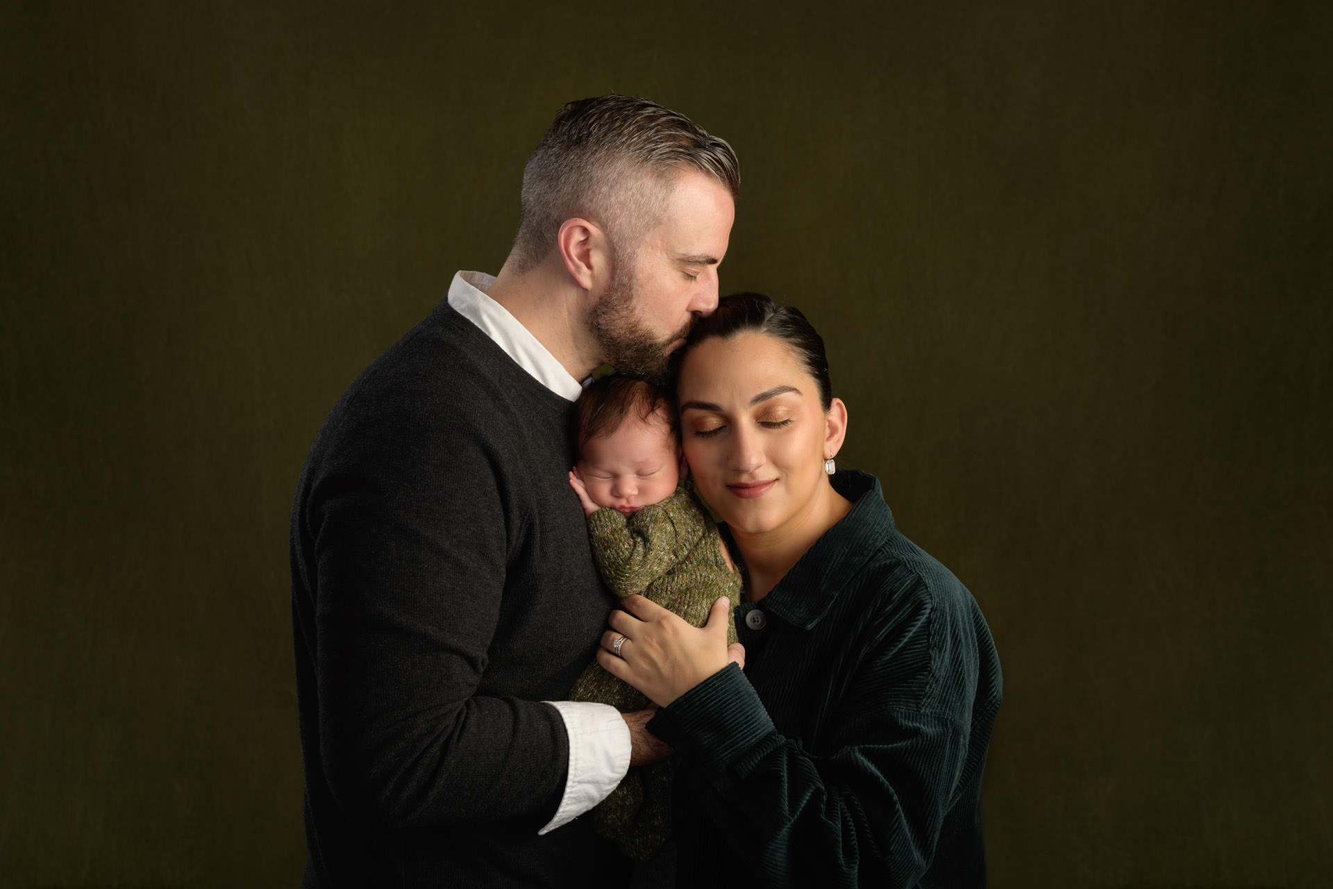 Family with newborn baby on a green background