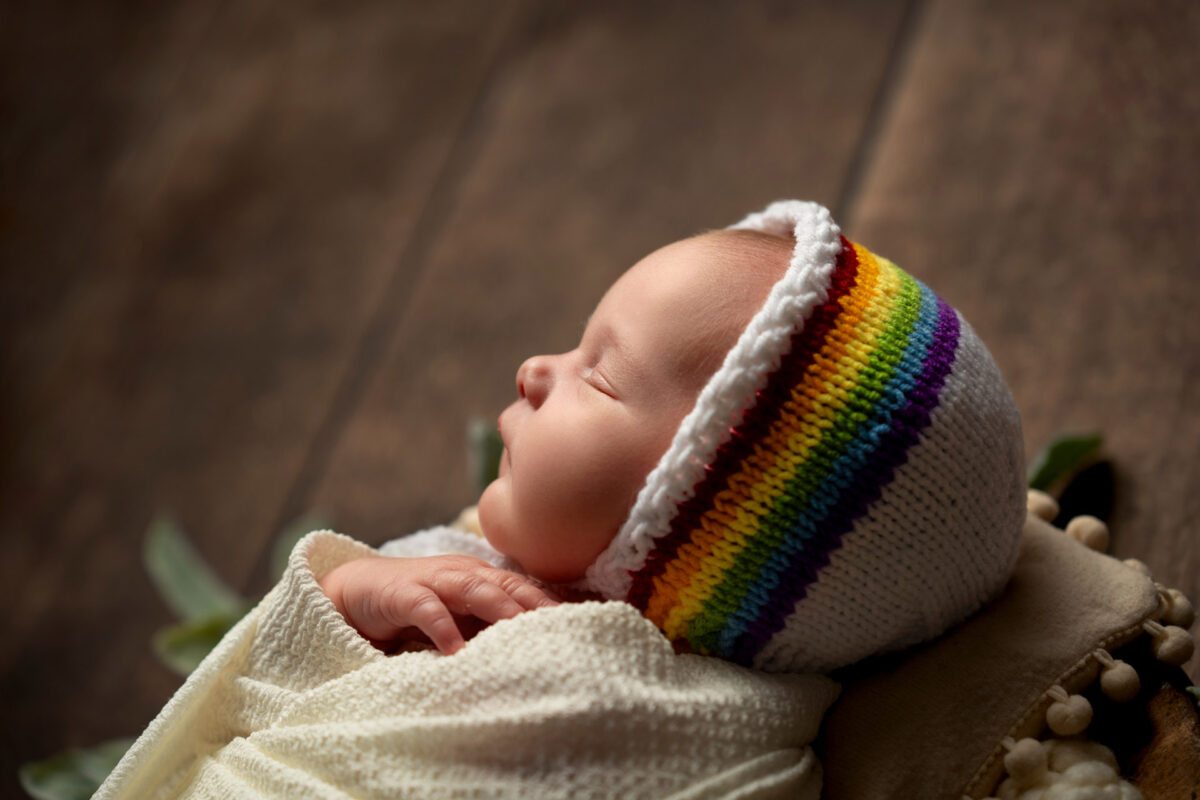 Newborn baby photo shoot wearing a rainbow bonnet